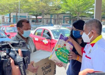 SARA Cinnasamy (tengah) menyerahkan sumbangan kotak makanan daripada PKSP kepada 70 pemandu teksi di pekarangan Stesen Komuter Shah Alam, Shah Alam hari ini.