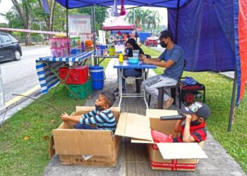 BEKAS pengusaha kantin sekolah, Paizal Husnidar, 39, dan isteri, Nur Indah Abdullah, 26, yang terkesan akibat pandemik Covid-19 setia menanti pelanggan di gerai mereka yang beroperasi di tepi jalan berhampiran Tasik Sri Rampai, Kuala Lumpur semalam. Pasangan itu turut ditemani anaknya Muhammad Haikal Ramadan Paizal, 7, (kanan) dan rakan, Adha Abdullah, 6. – UTUSAN/MUHAMAD IQBAL ROSLI