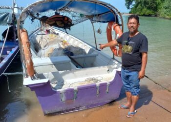 IBRAHIM Idris bersama bot miliknya yang kini tersadai di Jeti Nelayan Kampung Hailam, Tanjung Kling, Melaka. - UTUSAN/AMRAN MULUP