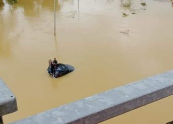 TIGA sekeluarga yang terperangkap atas bumbung kenderaan pacuan empat roda mereka gara-gara meredah banjir di Kampung Batu 10 berhampiran susur keluar Plaza Tol Chukai di Kemaman, Terengganu hari ini. - IHSAN ORANG AWAM