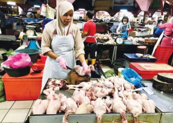SEORANG peniaga memotong ayam untuk pelanggan di Pasar Siti Khadijah, Kota Bharu Kelantan hari ini. - UTUSAN/ROSLIZA MOHAMED.