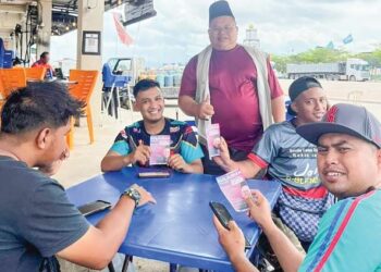 SULAIMAN Bakar (berdiri) mengedarkan risalah kepada pengundi muda DUN Tioman di Rompin, Pahang.