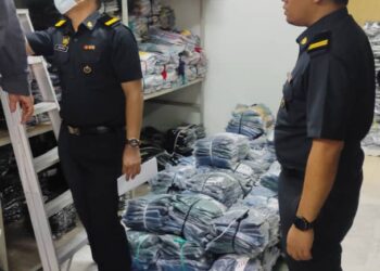 ANGGOTA penguat kuasa KPDNHEP Perak memeriksa barangan tiruan jenama terkenal yang dirampas dalam serbuan di sebuah rumah di Taman Chempaka, Ipoh,Perak, semalam. - IHSAN KPDNHEP PERAK