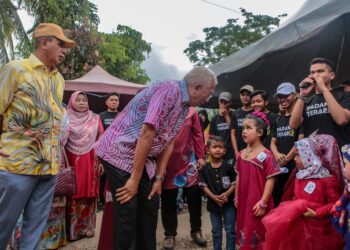 MAHDZIR Khalid berbual dengan seorang kanak-kanak selepas merasmikan Program Mesra Pengguna di Kampung Padang Nyior, Kuala Nerang di Padang Terap di sini, hari ini. -UTUSAN/ SHAHIR NOORDIN