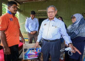 MUSTAPA Mohamed beramah mesra dengan seorang penduduk selepas menyampaikan sumbangan sempena lawatan turun padang ke daerah Kubang Pasu di Jerlun, Kedah,hari ini. - UTUSAN/ZAID MOHD. NOOR