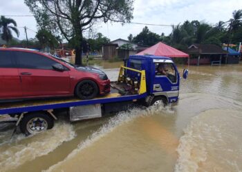 SEBUAH trak tunda membawa kenderaan yang terkandas selepas jalan dinaiki air dari  Jalan Air Hitam ke Kampung Nyior, Paka, Dungun, hari ini. - UTUSAN/NIK NUR IZZATUL HAZWANI NIK ADNAN
