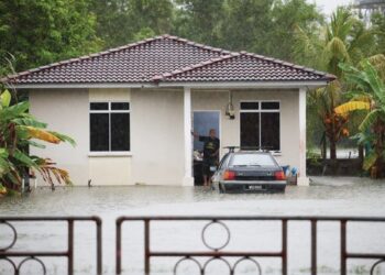 SEORANG penduduk melihat air yang naik di halaman rumahnya ekoran hujan lebat berterusan di Kampung Gong Tok Nasek, Kuala Terengganu, semalam. - UTUSAN/PUQTRA HAIRRY