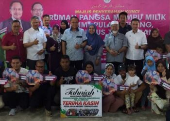 AHMAD Samsuri Mokhtar bergambar bersama penduduk yang menerima kunci rumah pangsa mampu milik di Pulau Redang, Kuala Nerus, Terengganu, hari ini. - FOTO/TENGKU DANISH BAHRI TENGKU YUSOFF