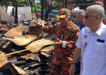 MOHAMMAD Anuar Mohd. Yunus (kanan) diberi penerangan mengenai kebakaran yang berlaku di Kampung Cina, Kuala Terengganu, hari ini. - FOTO/TENGKU DANISH BAHRI TENGKU YUSOFF