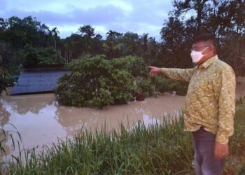 HANAFIAH Mat melihat rumah penduduk yang dinaiki air hingga paras bumbung di Kampung Jenang, Kemaman. - FOTO/NIK NUR IZZATUL HAZWANI NIK ADNAN