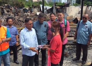 HANAFIAH Mat menyampaikan bantuan kepada salah seorang mangsa kebakaran di Kampung Cina, Kuala Terengganu, hari ini. - FOTO/TENGKU DANISH BAHRI TENGKU YUSOF