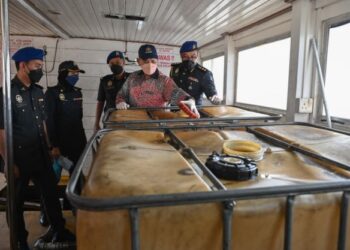 SAHARUDDIN Mohd. Kia (dua, dari kanan) melihat tangki penyimpan minyak diesel yang diseleweng dalam kapal pelancongan di Kuala Nerus, Terengganu. - FOTO/PUQTRA HAIRRY ROSLI