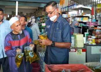 ROSOL Wahid memperkatakan sesuatu kepada seorang pengunjung yang membeli minyak masak peket selepas meninjau pada Program Jualan Keluarga Malaysia di Kuala Terengganu, hari ini. - FOTO/KAMALIZA KAMARUDDIN