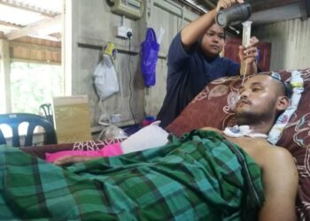 NUR Khairul Bariah Mokhtar memberi susu khas kepada Muhammad Faizal Hakimi Mat Jusoh yang lumpuh di Kampung Tengkawang, Hulu Terengganu. - UTUSAN/NOOR HAYATI MAMAT
