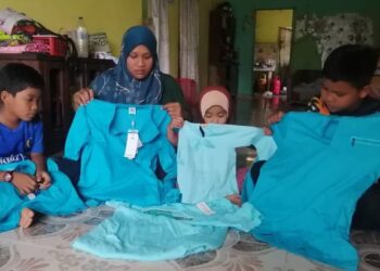 NOOR Shakilatur Shida Mamat (dua dari kiri) dan anak-anak menunjukkan baju raya dibeli arwah suaminya sebelum meninggal dunia di rumah mereka di Kampung Tok Dor, Ajil, Hulu Terengganu, semalam. - FOTO/NOOR HAYATI MAMAT
