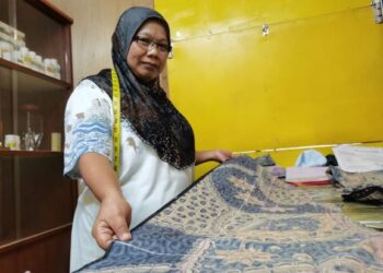 Rajimah Ismail menunjukkan tempahan kain yang masih belum sempat dijahit di kedainya di Pasar Am Papar, Sabah