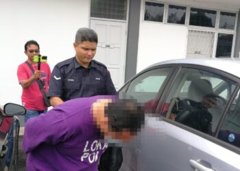 SUSPEK yang didakwa melakukan ugutan jenayah terhadap pegawai polis dibawa keluar dari kamar mahkamah selepas perintah reman dikeluarkan di Mahkamah Majistret Dungun, Terengganu, hari ini. - UTUSAN/NIK NUR IZZATUL HAZWANI NIK ADNAN