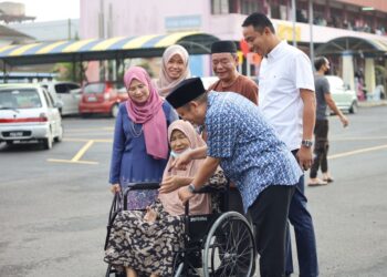 AHMAD Jazlan Yaakub (kanan) beramah mesra bersama seorang warga emas Nora Mohd Zin yang berkerusi roda selepas selesai mengundi di Sekolah Menengah Kebangsaan Machang, Kelantan. - UTUSAN/KAMARUL BISMI KAMARUZAMAN