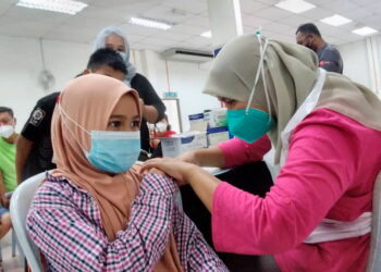 QAISARA Wafa Zara Shima Kamal (kiri) menerima suntikan vaksin Covid-19 di Dewan Komuniti Bagan Serai, Perak, semalam. – UTUSAN/WAT KAMAL ABAS