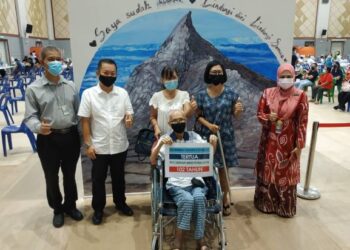 Anna (tiga kiri) bersama bapanya, Wong Kok Chew (duduk) merakamkan gambar kenangan bersama Chan Foong Hin (dua kiri) selepas menerima vaksin di PPV Dewan Kompleks Pentadbiran Persekutuan, di Kota Kinabalu hari ini.