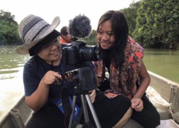 Ahli kumpulan yang terdiri daripada wanita komuniti Orang Asli menjalankan 
penggambaran video di sekitar perkampungan mereka.