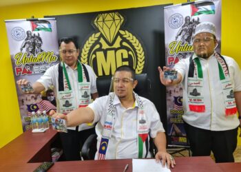 HISHAMMUDDIN Abdullah (duduk) menunjukkan wafer emas edisi khas 'Untukmu Palestin' di Wisma Makmur Gold di Kuantan, Pahang. - UTUSAN/SHAIKH AHMAD RAZIF