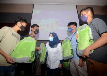 NORLIZA Abdul Rahim (kanan) menyerahkan beg baharu kepada pelajar yang menerima sumbangan pada majlis Kembali Ke Sekolah 2022 di Universiti Sains Malaysia (USM), Pulau Pinang, semalam.