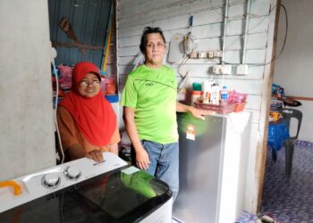 Azman Ibrahim dan Asmah Daud menunjukkan mesin basuh dan peti sejuk sumbangan MAINJ di Kampung Parit Ibrahim, Pontian, Johor.