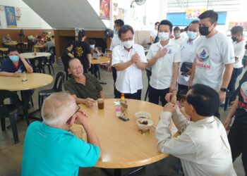 Mohd. Shafie Apdal (berdiri kiri) menyantuni penduduk setempat ketika mengadakan 'walk-about' di sekitar Bukit Batu, Kulai, hari ini.