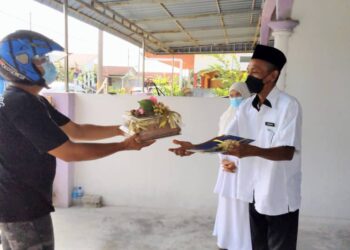 AZEMAN Mat (kiri) menerima watikah persaraan yang dihantar oleh pihak sekolah kepadanya melalui khidmat penghantar barangan di Gelung Pepuyu, Bota dekat Parit semalam. - UTUSAN/MOHAMAD HAFIZI MOHD SAID