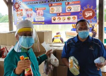 CHE Abdullah Mat Nawi (kiri) membantu mengagihkan bekalan makanan kepada penduduk di PKPD Kepulauan Tumpat, Kelantan hari ini. - UTUSAN/YATIMIN ABDULLAH