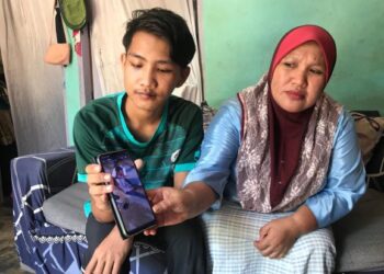 FAQIH Yusof (kiri) menunjukkan gambar selepas dia menjadi mangsa langgar lari di Hentian Gua Musang, Februari lalu, di rumahnya di Kampung Tanah Putih, Gua Musang, Kelantan, baru-baru ini. –UTUSAN/AIMUNI TUAN LAH