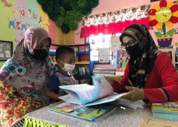 TENGKU Nor Kamizan Tengku Kamarulzaman (kanan) menyerahkan lembaran kerja kepada seorang ibu di Kampung Lepan Jaya, Gua Musang, Kelantan untuk mengikuti PdPR. – UTUSAN/AIMUNI TUAN LAH