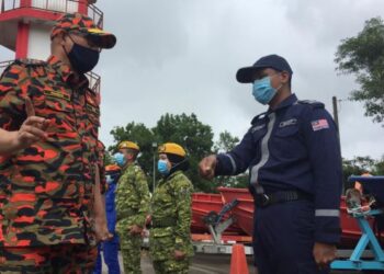 MOHAMMAD Hamdan Wahid (kiri) beramah mesra dengan anggota SMART yang terlibat dalam operasi banjir di Rantau Panjang hari ini.-UTUSAN/YATIMIN ABDULLAH