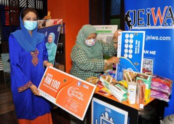 ZAITON Ismail (kanan) membuat gimik dengan memasukkan replika baucar ke dalam tabung khas sambil diperhatikan Nor Fadilah Mohamed sempena Majlis Pelancaran Jeiwa Charity Boutique di Paradigm Mall, Johor. -UTUSAN/RAJA JAAFAR ALI