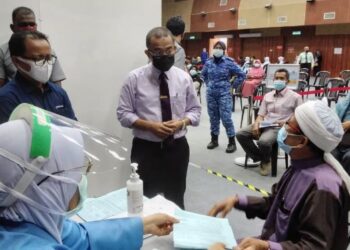 NOOR Azmi Ghazali (tengah) berbual dengan seorang penerima vaksin ketika melawat PPV Dewan Kerian Permai di Parit Buntar hari ini. - UTUSAN/WAT KAMAL ABAS