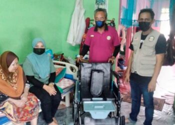 SUHAILEY Saad (dua dari kiri) menerima sumbangan kerusi roda untuk ibunya daripada wakil Yayasan Amal Malaysia Cawangan Perak di sini Selinsing, Bagan Serai semalam. - UTUSAN/WAT KAMAL ABAS