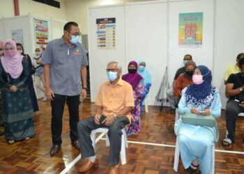 MOHD. Faizal Abdul Manaf menyantuni penerima vaksin dalam fasa kedua Program Imunisasi Covid-19 Kebangsaan di PPV Dewan Dato' Bahaman, Kuala Pilah hari ini.-UTUSAN/ZAKKINA WATI AHMAD TARMIZI.