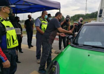ROSLEE Chik (kiri) bersama Ahmad Samsuri Mokhtar mengagihkan juadah berbuka puasa kepada pengguna jalan raya di sekatan jalan raya (SJR) Perasing di Kemaman petang semalam.- UTUSAN/NIK NUR IZZATUL HAZWANI NIK ADNAN