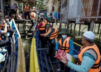 Anggota sukarelawan menyerahkan bantuan kepada penduduk Kuala Sungai Balung pada Misi Bantuan Kemanusiaan Sabah oleh Muslim Care Malaysia (MCM) bagi meringankan beban yang terjejas akibat wabak Covid-19 di Semporna , semalam. – MINGGUAN/FARIZ RUSADIO