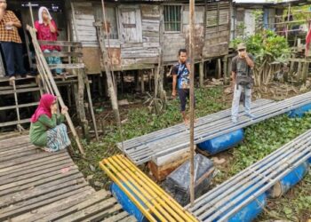 PENDUDUK menunjukkan sangkar pecah yang hanyut sehingga ke penempatan mereka di Kampung Batak Rabit di Teluk Intan, semalam. – UTUSAN/AIN SAFRE BIDIN