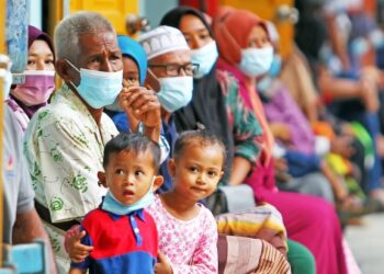 ORANG ramai menunggu giliran untuk menjalani ujian calitan Covid-19 di dewan terbuka SK Pulau Beluru, Tumpat. – UTUSAN/ZULHANIFA SIDEK