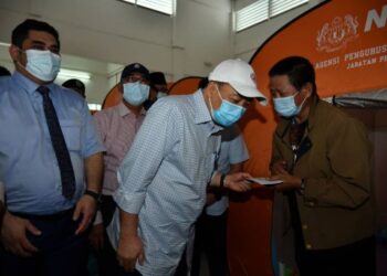 HAJIJI NOOR (tengah) diiringi oleh Ir.  Shahelmey Yahya (kiri) menyampaikan bantuan kepada mangsa kebakaran Kampung Meruntum yang ditempatkan di Dewan Sri Serigai Putatan, Sabah