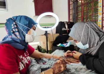 NANEULHUSNA Maasum melukis inai perhiasan pilihan pelanggannya ketika ditemui di Taman Gunung Mas, Tampin, semalam.