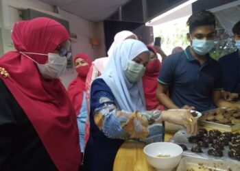 HARYATY Hamdzah (kiri) melihat Munira M. Yusop (tengah) meletakkan hiasan biskut pada Majlis Ramah Mesra Program Ceria Cookies di Kolej Komuniti Kota Melaka, Melaka. - UTUSAN/MUHAMMAD SHAHIZAM TAZALI