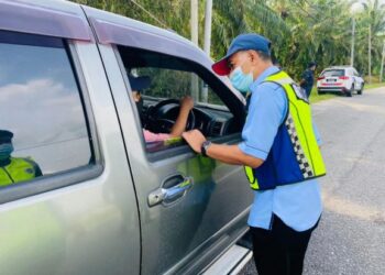 BARUDIN Wariso memeriksa kenderaan di SJR di Kilometer 3, Jalan Gelung Pepuyu-Beruas di Parit hari ini. - UTUSAN