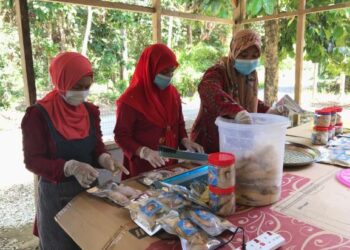 Iah Idris (kiri) menghasilkan produk ikan pekasam bersama tiga lagi sahabatnya di Kampung Pasir Tumbuh, Gua Musang, Kelantan, hari ini. – UTUSAN/AIMUNI TUAN LAH