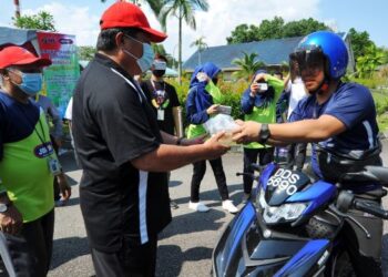 MAZLAN Bujang (dua dari kiri) menyampaikan bubur lambuk secara pandu lalu kepada seorang penunggang motosikal sempena majlis Bubur Lambuk Johorfm Pandu Lalu Sucinya Ramadan di Kompleks Penerangan dan Penyiaran Sultan Iskandar, Johor. -UTUSAN/RAJA JAAFAR ALI