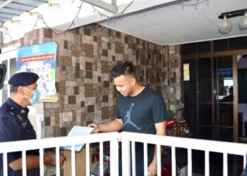 MOHD. IFWAT AKMAL CHEK KASSIM (kanan) menunjukkan surat kebenaran rentas negeri selepas polis yang melakukan operasi pemantauan dan pemeriksaan singgah di rumah penjaga gol Kedah itu Taman Bukit Kubu, Kuala Perlis, hari ini.-UTUSAN/NAZLINA NADZARI