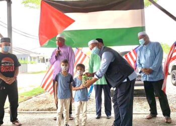 MUHAMMAD Harith Mohd. Hafizan (tengah) dan Muhammad Hakeem menyerahkan tabung syiling  kepada Mohd. Johari Ismail dalam majlis di Parit hari ini. - UTUSAN/MOHAMAD HAFIZI MOHD. SAID